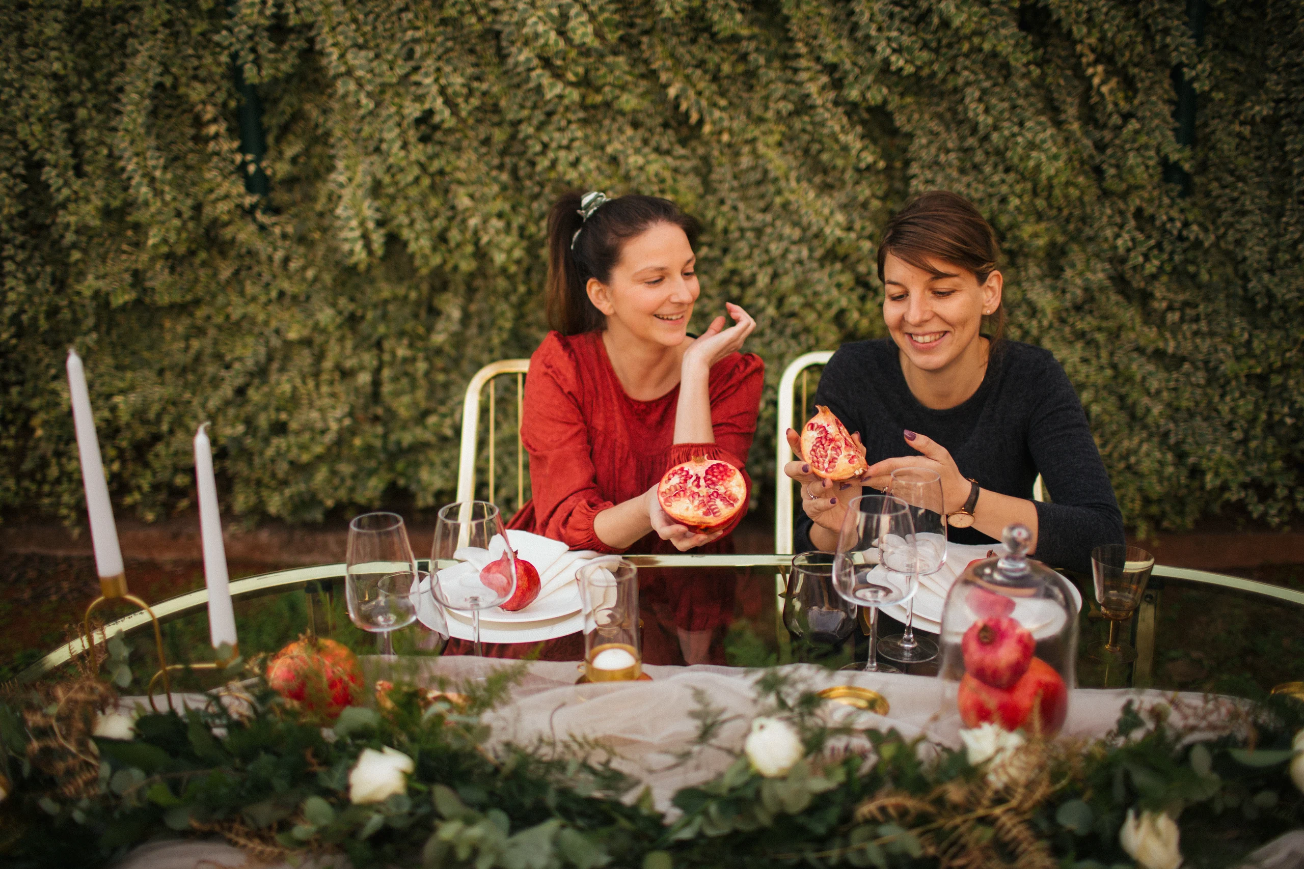 Katarina and Marija sharing pomegranates at a decorated table
